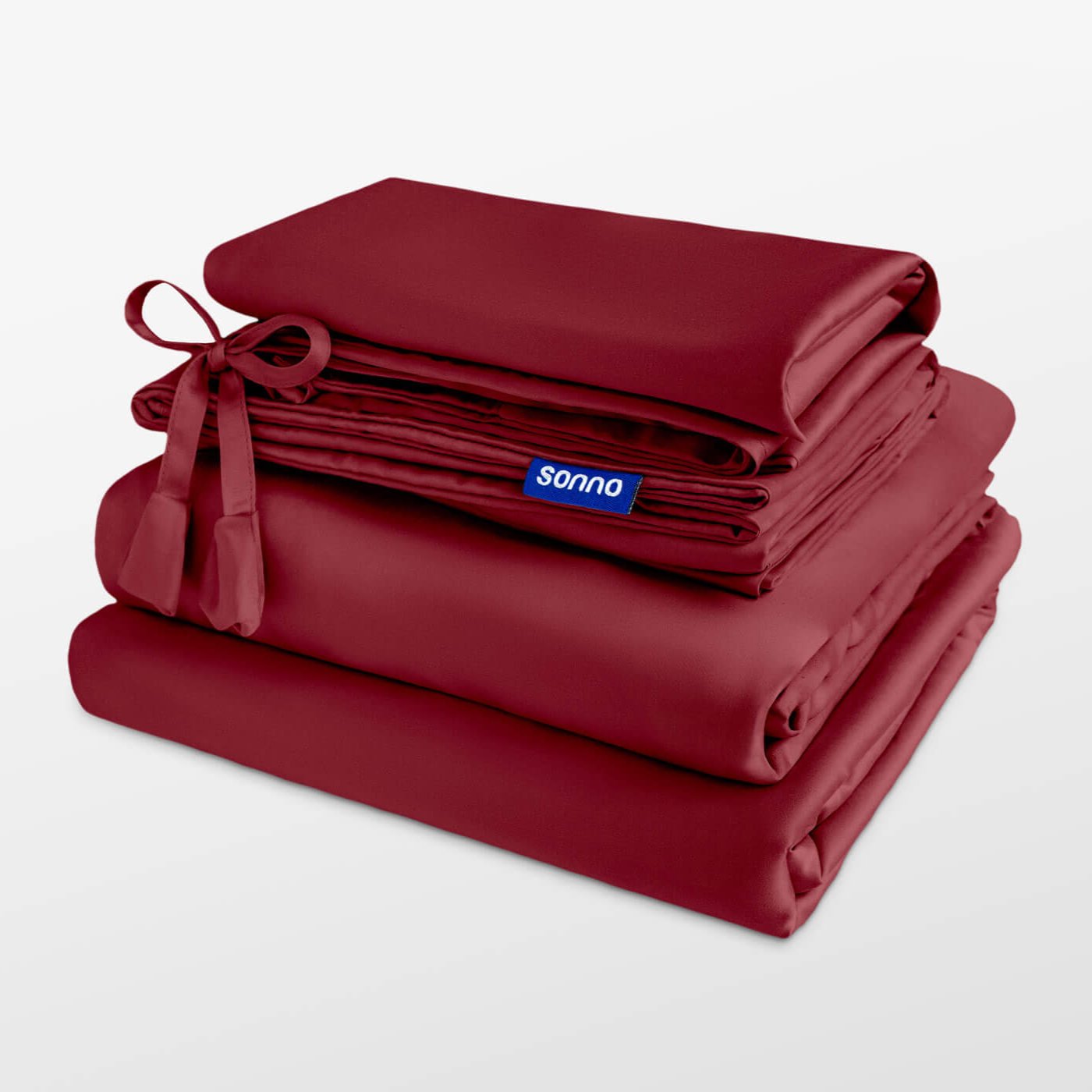 Stack of red bedding with 'sonno' brand label on a light gray background
