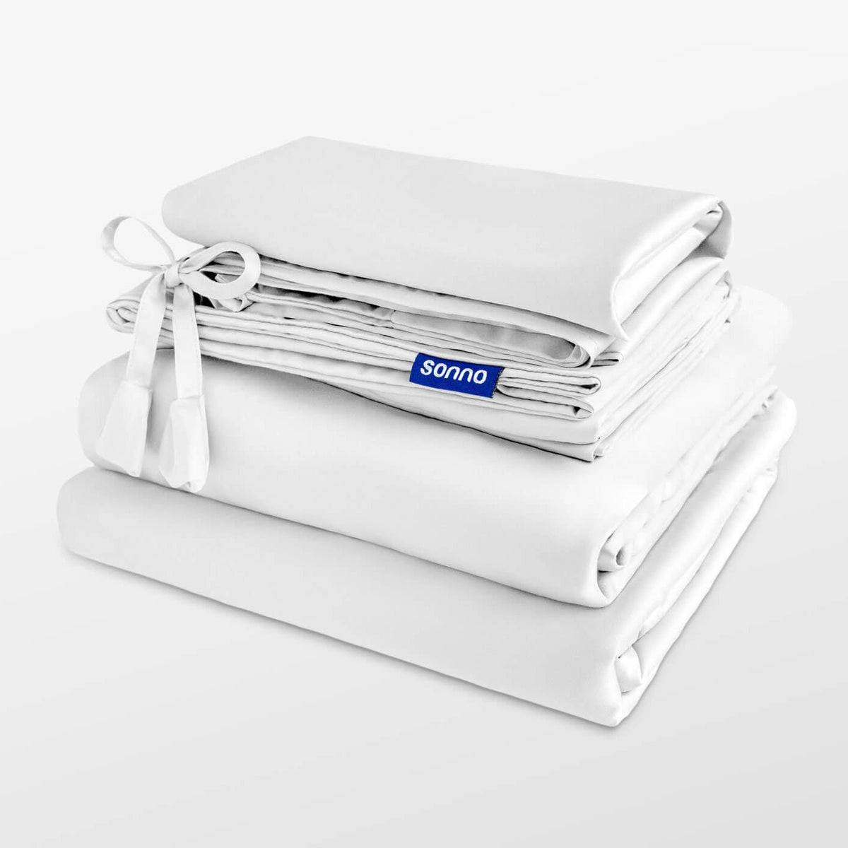 Folded white bedding set with 'sonno' branding on a light gray background
