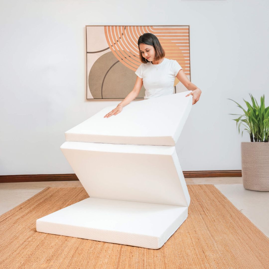 Woman sitting on a modern white stool in a minimalistic room with a plant and abstract art.
