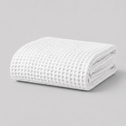 Folded white textured Sonno waffle bamboo blanket on a grey background