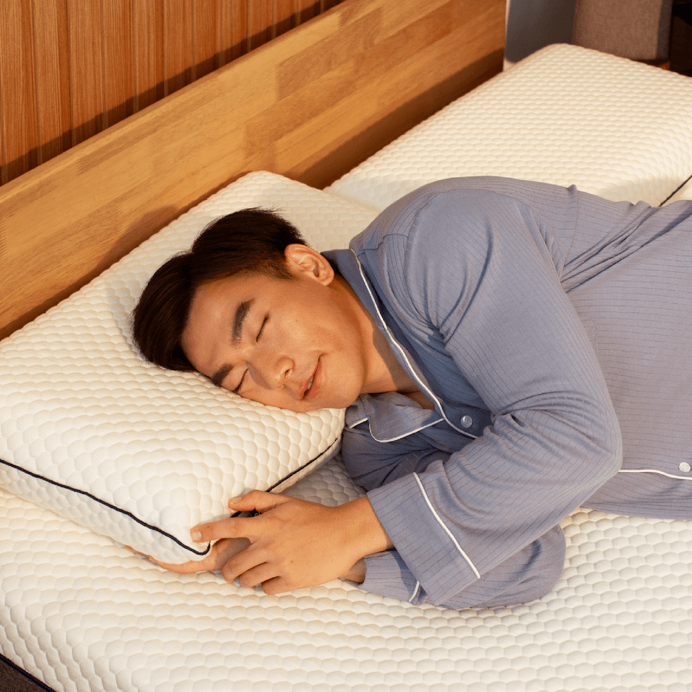 A person sleeping comfortably on a white memory foam Sonno pillow